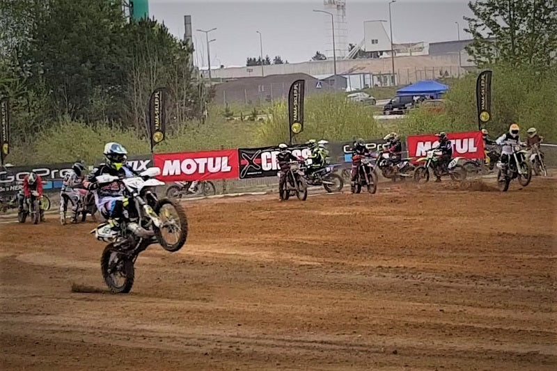 Zdjęcie z toru wyścigowego Mistrzostw Polski Strefy Północnej , z motocyklistą na torze i innymi motocyklistami w tle