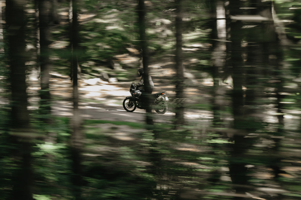 motocyklista jadący po trudnym terenie w lesie motorem adventure