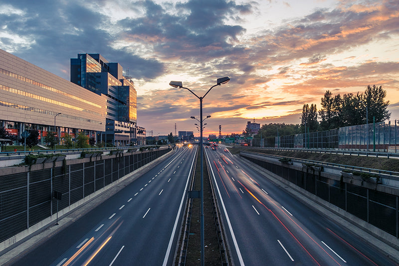 Autostrada w mieście w tle zachodzące słońce i budynki biurowe