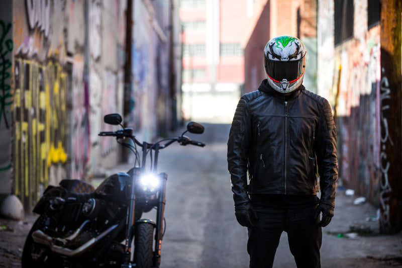 Motocyklista w kasku stoi obok motocykla