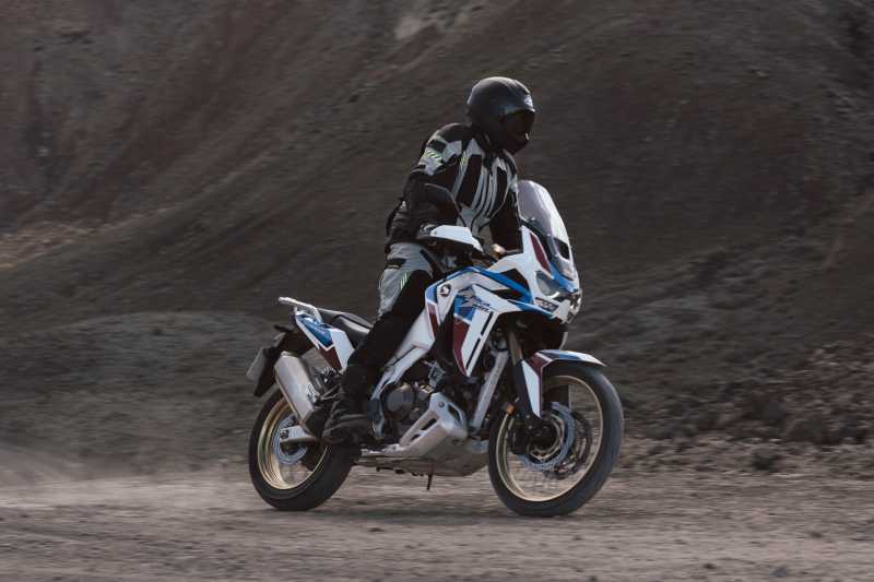 Motocyklista na motocyklu w kurtce Rebelhorn Patrol na piaszczystej drodze.