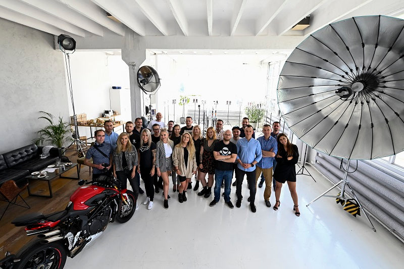 Grupa osób obok motocykla pozująca do zdjęcia