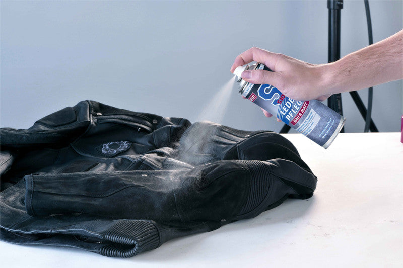 Ręka trzyma spray S100 Leder-Reiniger do impregnacji skóry nad kurtką motocyklową
