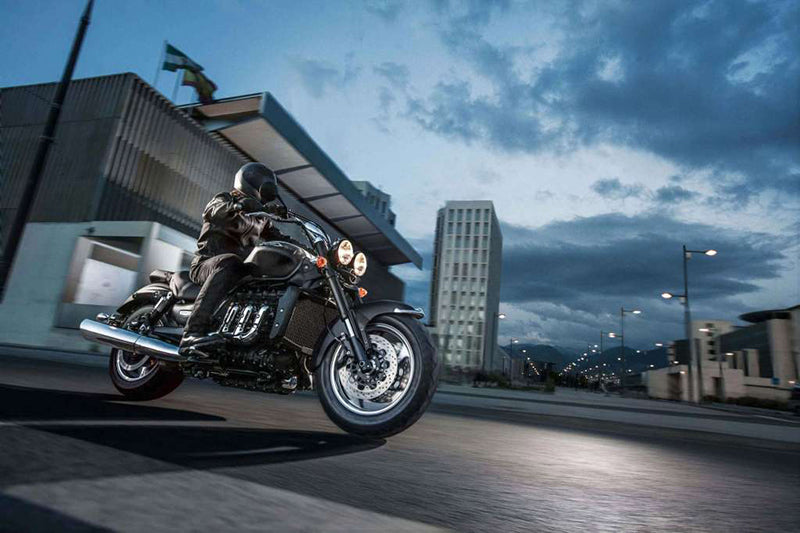 Motocyklista na czarnym motocyklu przy budynkach podczas pochmurnej pogody