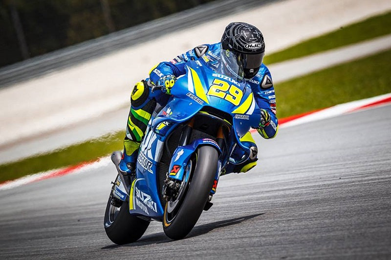 Andrea Iannone na torze wyścigowym podczas wyścigu, na niebiesko-żółtym sportowym motocyklu, w kasku HJC