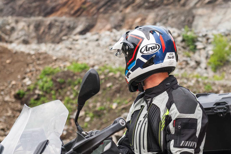 motocyklista w kasku Arai stoi wśród skał i się rozgląda