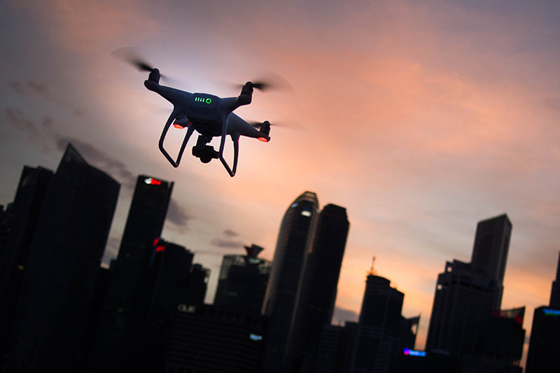 Dron lecący nad miastem, w tle zachodzące słońce