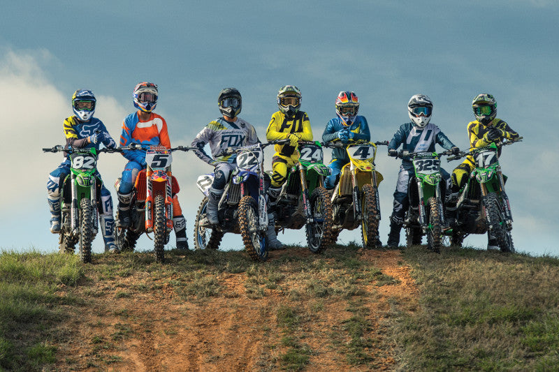 Grupa motocyklistów MX lub enduro w ubraniach motocyklowych fox i kaskach motocyklowych, siedzą na motocyklach na szczycie skarpy