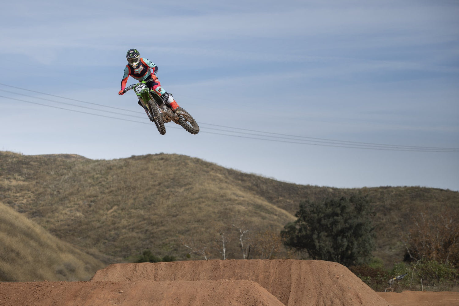 Motocyklista offroadowy w kasku na MX, skaczący nad torem motocrossowym