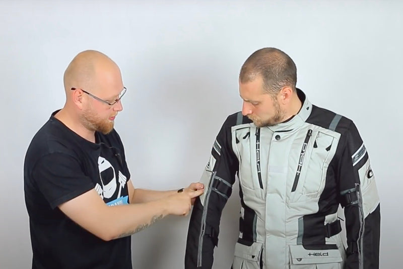 Mężczyzna w kurtce motocyklowej marki Held Hakuna Matata, drugi mężczyzna omawiający tę kurtkę