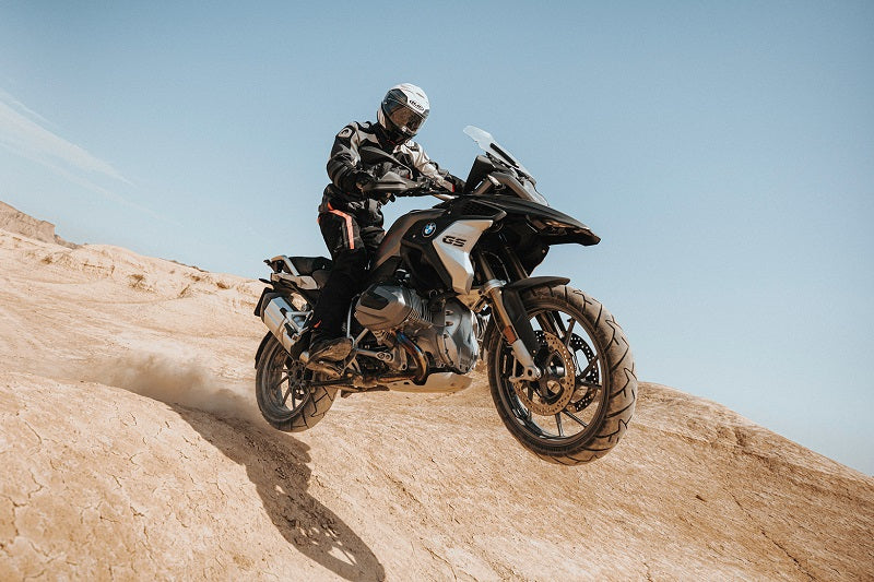 Motocyklista offroadowy w kasku na motocyklu, zjeżdżający ze stromej piaszczystej górki