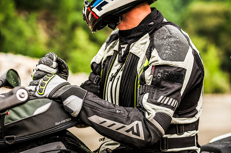 Motocyklista w czasie wyprawy, siedzi na motocyklu, zbliżenie na kufry sw motech i tekstylną kurtkę motocyklową rebelhorn patrol