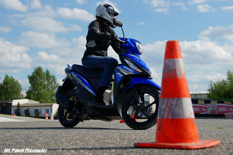 osoba na skuterze suzuki jeździ po placu manewrowym