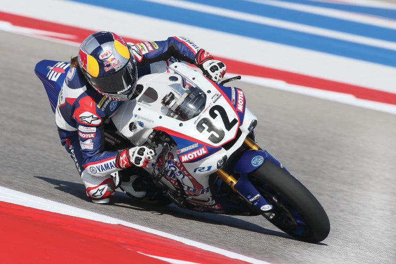 Motocyklista na torze wyścigowym pędzący przez tor na sportowym motocyklu w kasku z logiem red bull