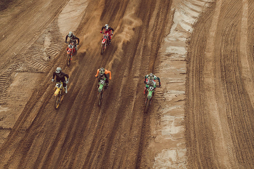grupa motocyklistów jedzie po torze motocrossowym