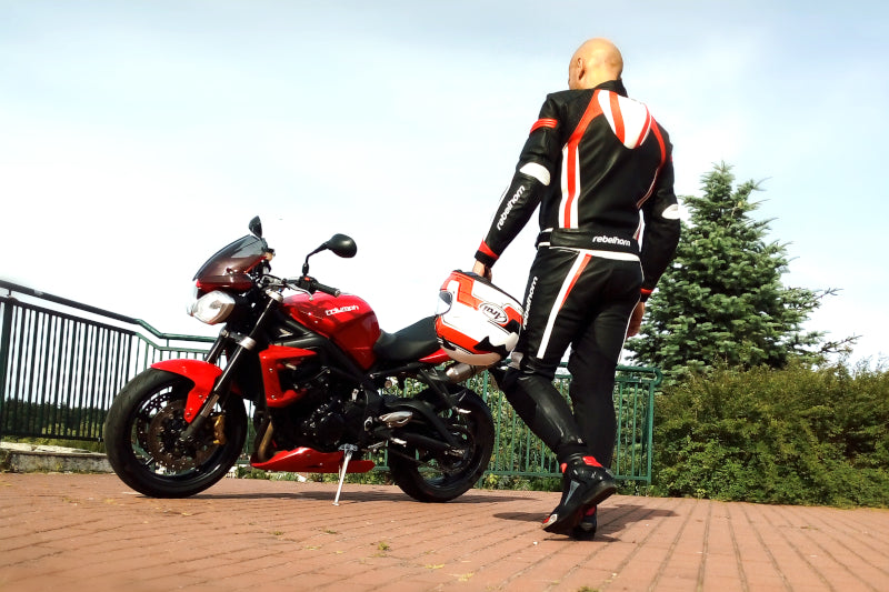 Motocyklista trzymając kask Arai Profile V idzie w kierunku motocykla