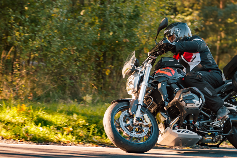 Motocyklista podczas jazdy na motocyklu, ubrany z kombinezon motocyklowy i kask