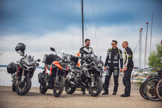 motocykliści na tle mariny, obok nich motocykle typu BMW i Suzuki