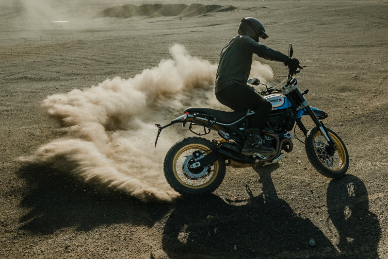 Motocyklista kurzy piachem na ostrym zakręcie