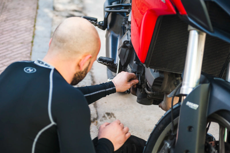 łysy motocyklista wymienia olej w motocylu