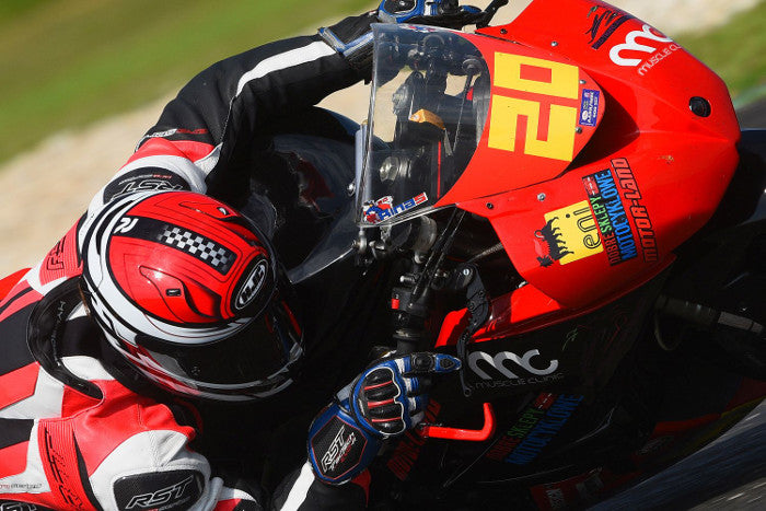 Paweł Rinas na torze motocyklowym, na czerwonym motocyklu, w kombinezonie i kasku motocyklowym