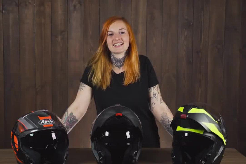 Ruda dziewczyna uśmiecha się stojąc nad trzema kaskami motocyklowymi