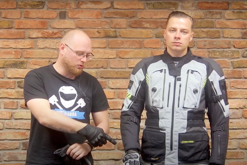 dwoje mężczyzn stoi przy ścianie, prezentują odzież motocyklową