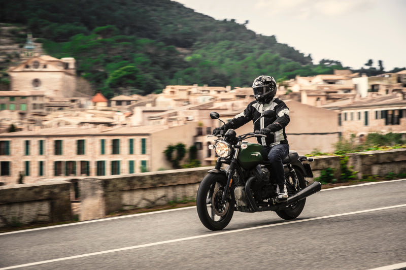 motocyklista jedzie samotnie przez piękną okolicę, w tle miasteczko i góry