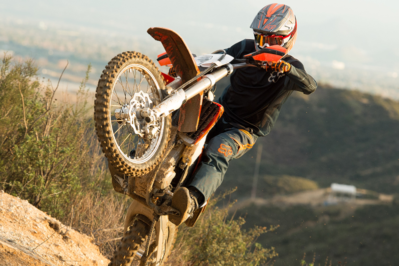 Motocyklista enduro w kasku motocyklowym, robiący manewr na hałdzie piachu