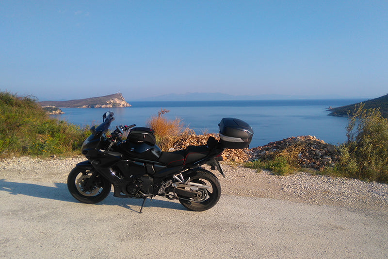 Czarny motocykl na piaszczystej drodze z widokiem na morze