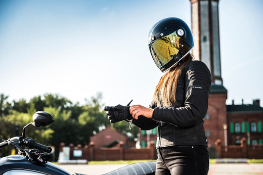 motocyklistka stoi pod latarnią morską w niechorzu i zakłada damskie rękawice motocyklowe na miasto