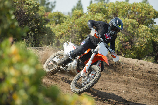 Motocyklista offroadowy podczas jazdy po torze na motocyklu i w kasku szczękowym fox