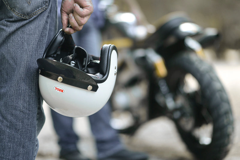 motocyklista trzyma kask w ręku i stoi naprzeciwko swojego motocykla