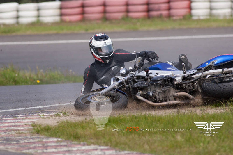 Motocyklista w kombinezonie motocyklowym ozone i kasku podczas upadku na torze motocyklowym