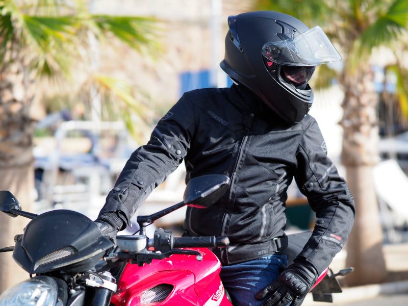 mężczyzna siedzący na czerwonym motocyklu ma na sobie czarną letnią kurtkę na motor ozone jett ii