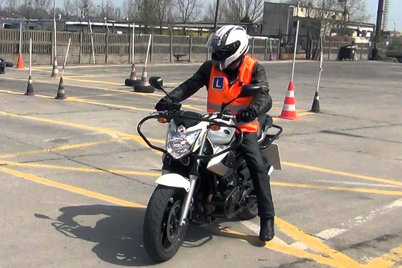 motocyklista na placu siedzi na motocyklu w białym kasku 