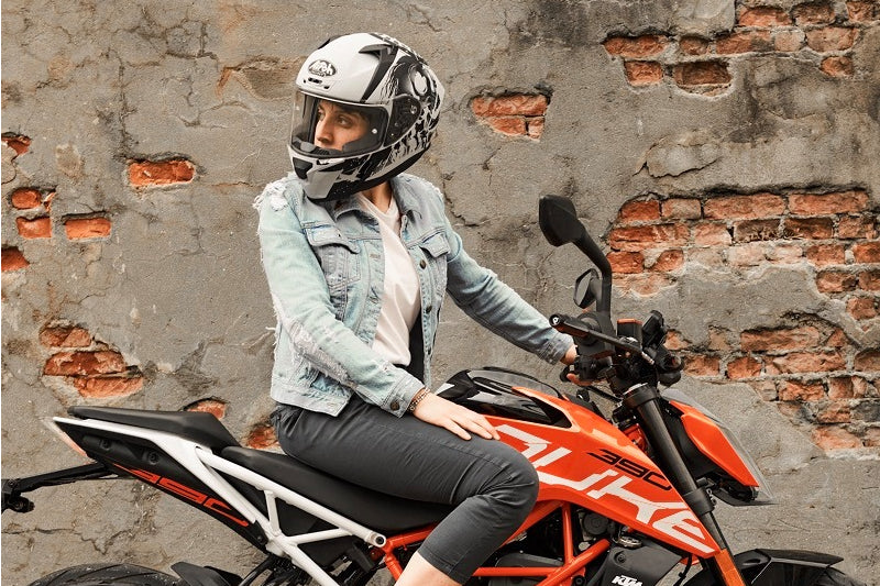 Motocyklistka siedzi na motocyklu w kasku Airoh
