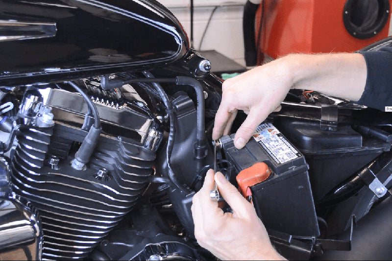 mężczyzna montuje akumulator w motocyklu