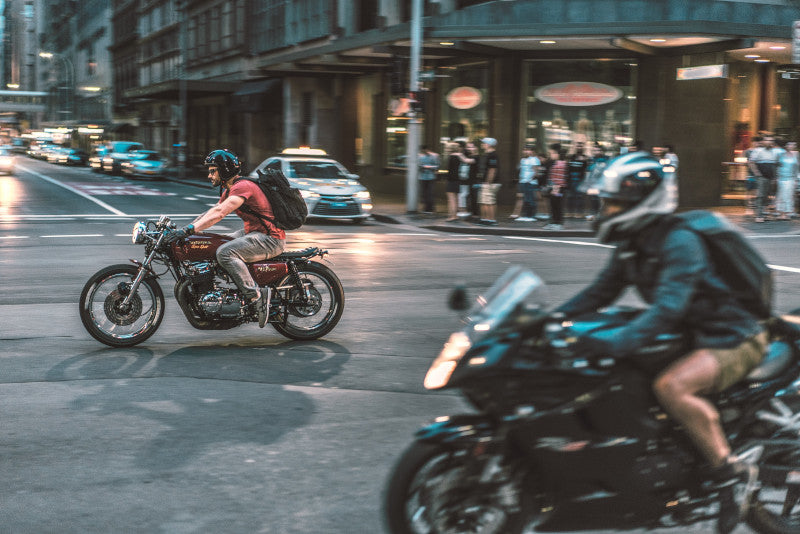 Motocykliści w kaskach motocyklowych jadący ulicą w mieście wieczorową porą
