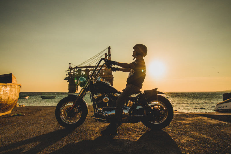 motocyklista na chopperze stoi nad brzegiem morza w industrialnej przestrzeni