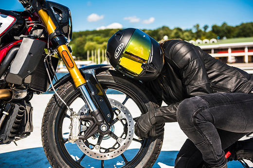 Motocyklista przytulający się do przedniego koła motocyklu 