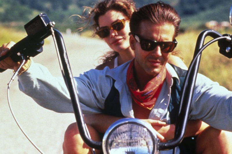 Kadr z filmu Dzika Orchidea, z parą jadącą na motocyklu typu chopper, w tle droga 