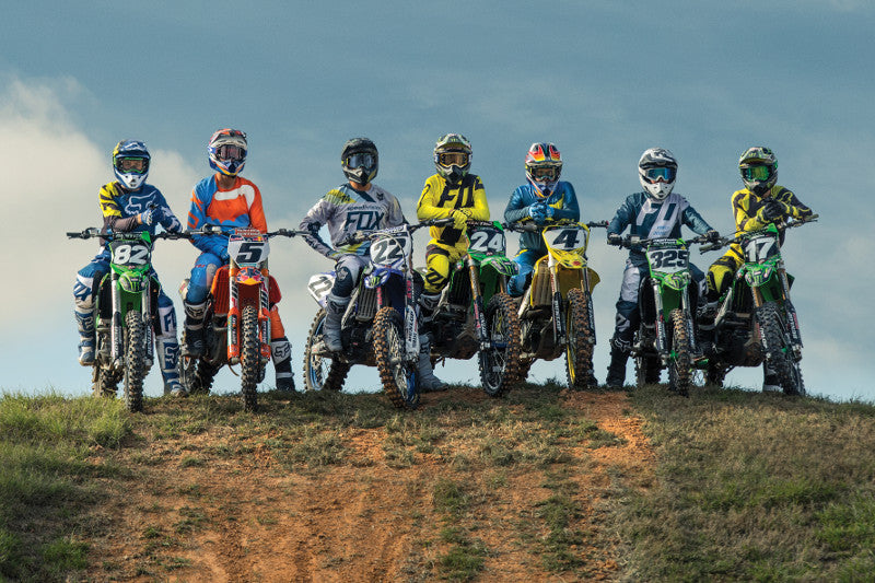 Grupa motocyklistów MX lub enduro w ubraniach motocyklowych fox i kaskach motocyklowych, siedzą na motocyklach na szczycie skarpy 