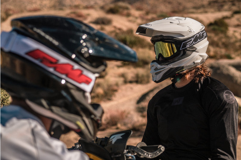 Dwóch motocyklistów offroadowych w kaskach szczękowych patrzących na siebie. 