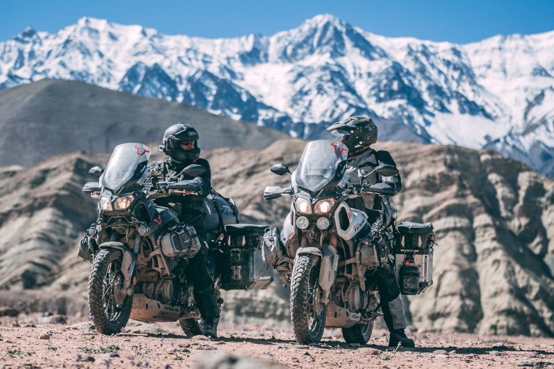 Dwójka motocyklistów w górzystych terenach, siedzi na motocyklach turystycznych w obraniu i kasku motocyklowym