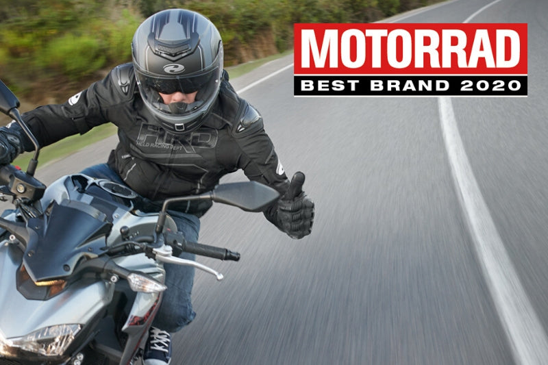 motocyklista w zakręcie pokazuje uniesiony kciuk, w rogu jest logo magazynu motorrad
