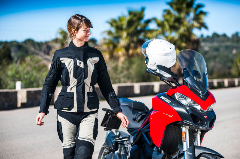 kobieta przy motocyklu się uśmiecha, idzie w kierunku aparatu