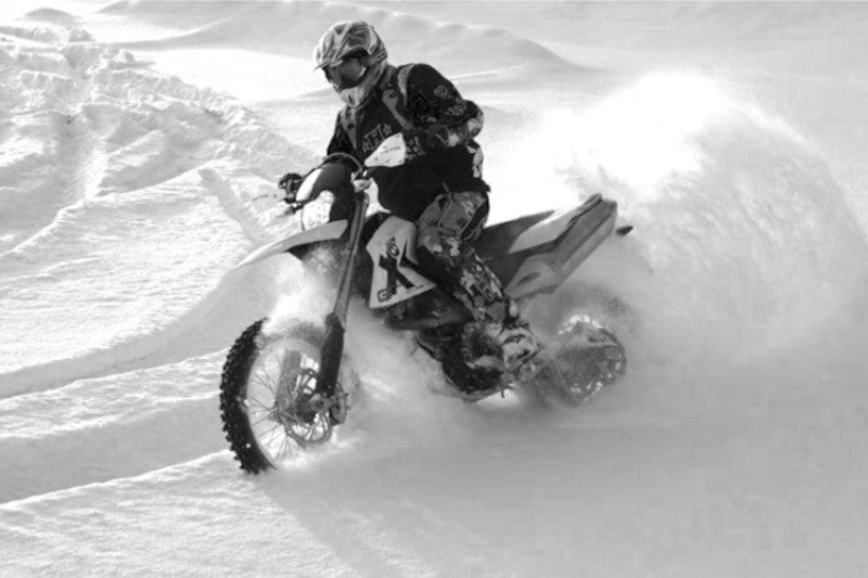 Motocyklista na motocyklu jedzie po śniegu 