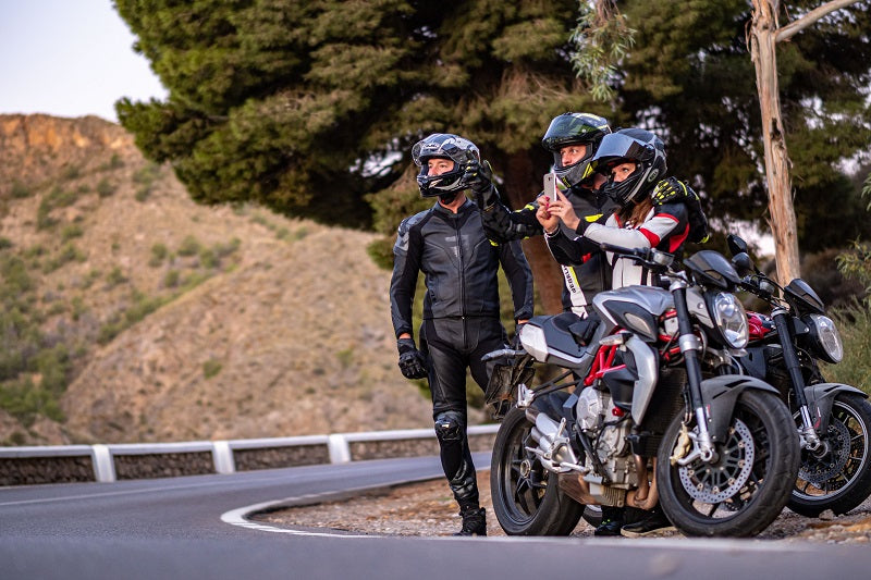troje motocyklistów stoi na poboczu ze swoimi motocyklami