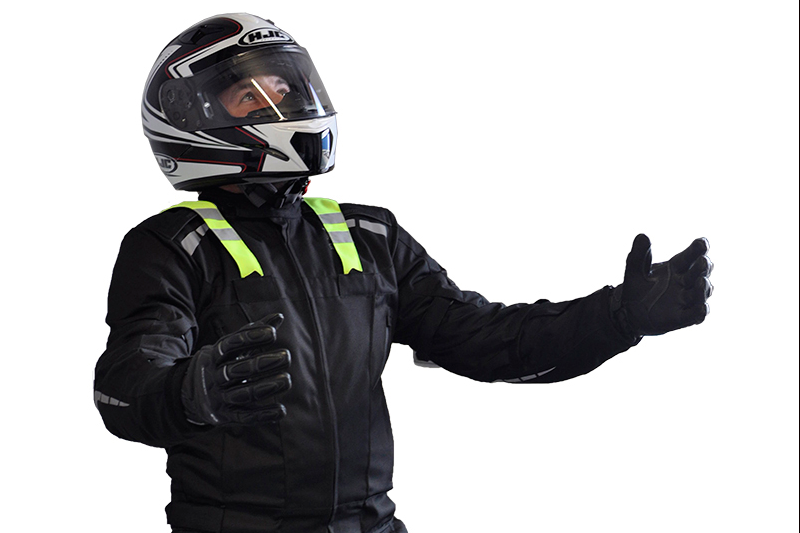 Uradowany motocyklista w czarnej motocyklowej kurtce tekstylnej z odblaskami i kasku motocyklowym HJC